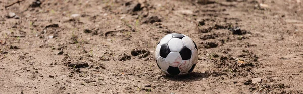 Panoramic shot of football on dirty road on urban street — Stock Photo