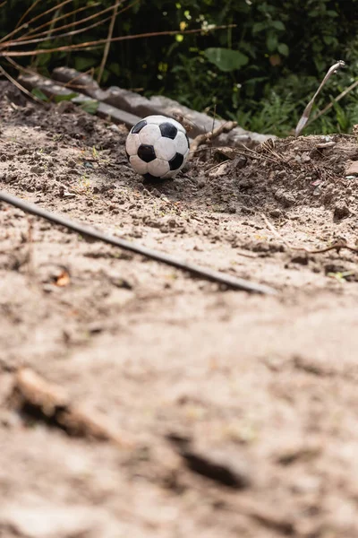 Вибірковий фокус футбольного м'яча на землі брудної дороги на міській вулиці — стокове фото