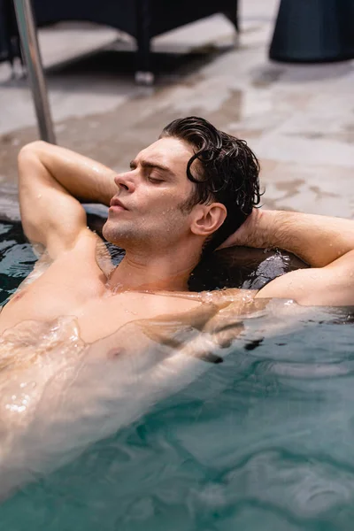 Hombre sin camisa y mojado relajándose en la piscina - foto de stock