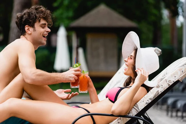 Alegre pareja sonriendo mientras tintineo alcohol cócteles - foto de stock