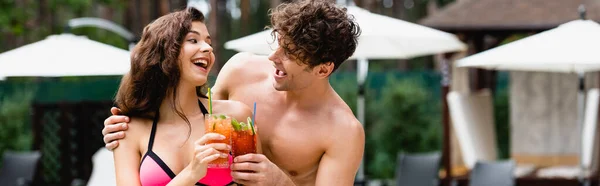 Plano panorámico de feliz pareja sacudiendo cócteles y mirándose el uno al otro - foto de stock