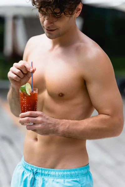 Homem bonito e sem camisa segurando vidro com coquetel — Fotografia de Stock