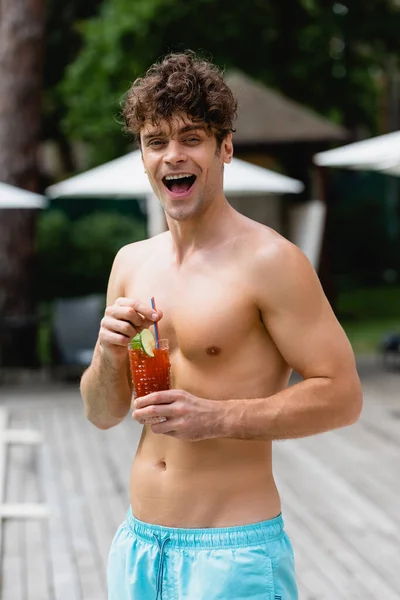 Excited and shirtless man holding glass with cocktail — Stock Photo