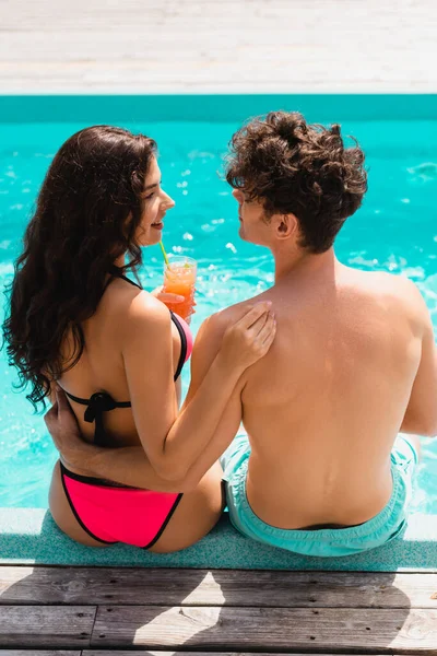 Vista ad alto angolo di donna felice guardando l'uomo e tenendo cocktail vicino alla piscina — Foto stock