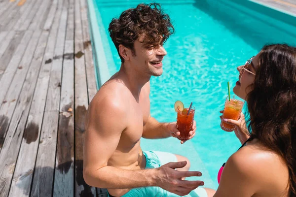 Fröhliches Paar in Badebekleidung mit Alkoholcocktails in Schwimmbadnähe — Stockfoto