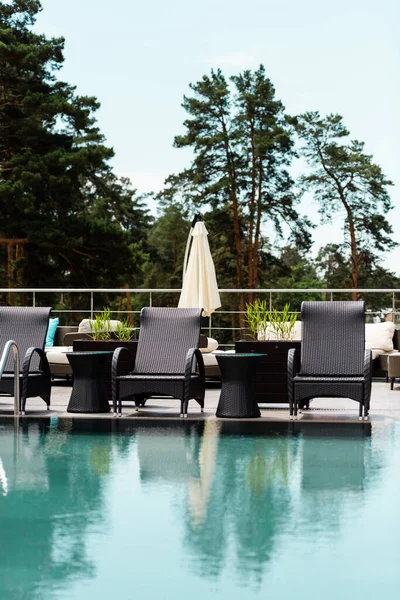 Moderni lettini vicino alla piscina con acqua blu — Foto stock