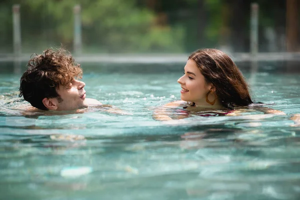 Селективное внимание счастливого мужчины и женщины, плавающих в бассейне — стоковое фото