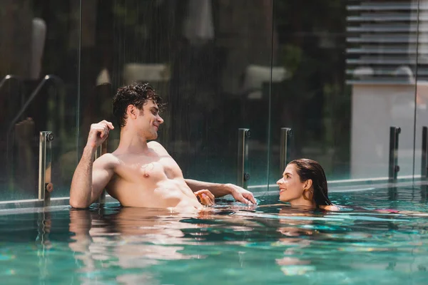 Hemdloser Mann schaut attraktive Frau im Schwimmbad an — Stockfoto