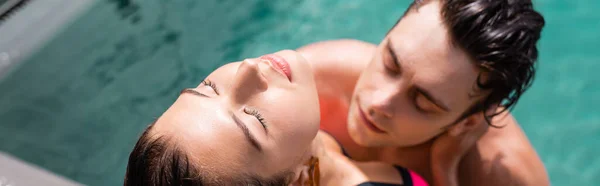 Panoramic concept of attractive woman with closed eyes near man in swimming pool — Stock Photo