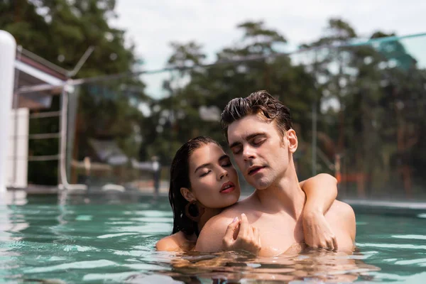 Sexy mujer abrazando muscular hombre en piscina - foto de stock