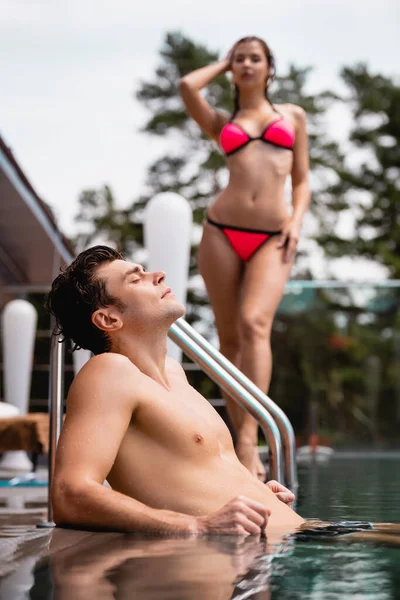 Selective focus of muscular man in swimming pool near woman in swimsuit — Stock Photo