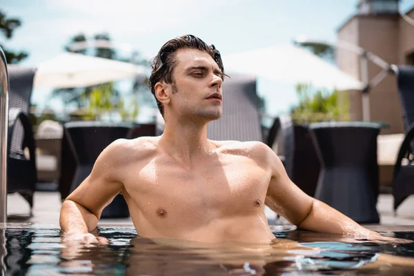 Hombre sin camisa y sexy mirando hacia otro lado en la piscina - foto de stock