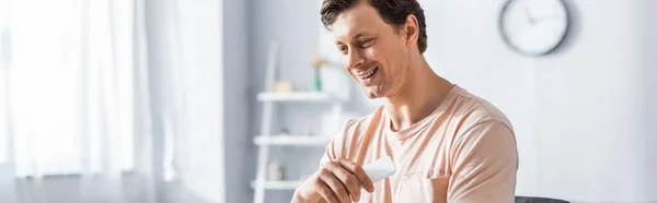 Imagem panorâmica de um freelancer sorridente segurando smartphone em casa — Fotografia de Stock