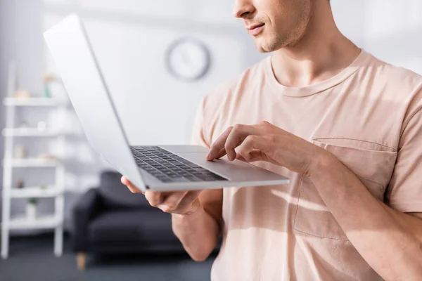 Vista recortada de freelancer sosteniendo y escribiendo en el ordenador portátil en casa, ganando concepto en línea - foto de stock