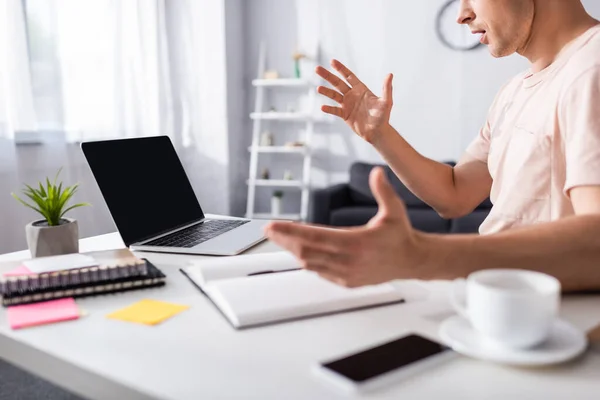 Cropped view of shocked freelancer sitting near laptop and stationery on table at home, concept of earning online — Stock Photo