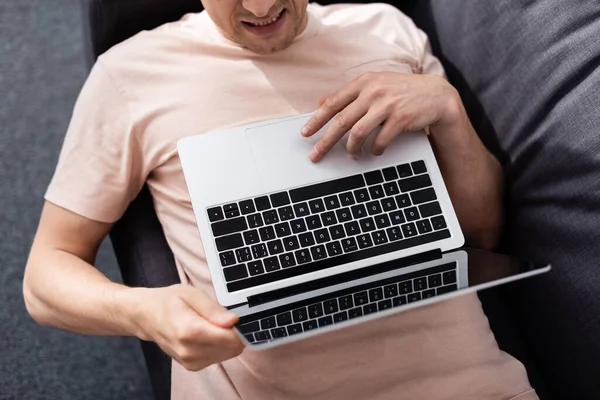 Vista superior del freelancer usando el ordenador portátil con la pantalla en blanco mientras que miente en el sofá en el país, concepto de ganar en línea - foto de stock