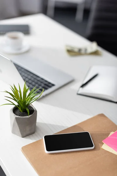 Selective focus of smartphone with blank screen near laptop and notebook on table, earning online concept — Stock Photo