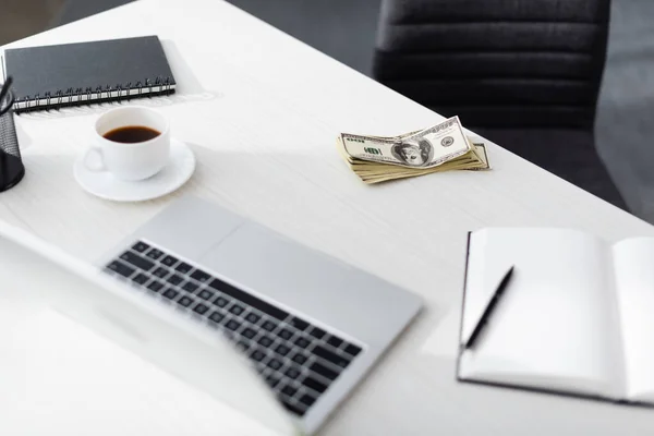 Focus selettivo di dollari vicino laptop, notebook e tazza di caffè sul tavolo, guadagnando concetto online — Foto stock