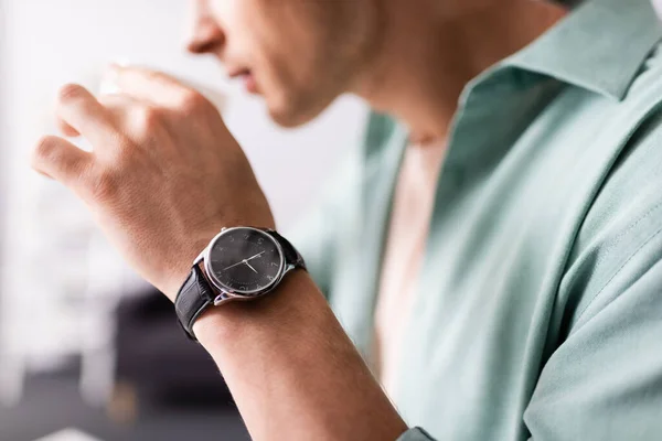 Cropped view of man in wristwatch drinking coffee, concept of time management — Stock Photo