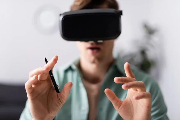 Concentration sélective de l'homme dans le casque vr tenant stylo à la maison — Photo de stock