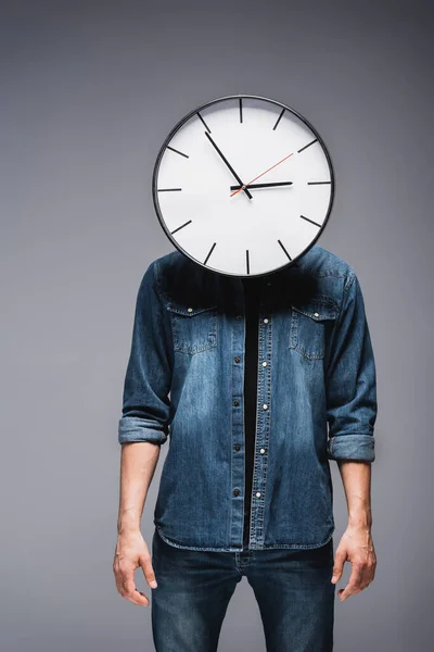 Hombre con reloj en la cabeza de pie sobre fondo gris, concepto de gestión del tiempo - foto de stock