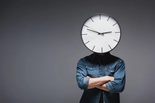 Young man with clock on head and crossed arms on grey background, concept of time management — Stock Photo