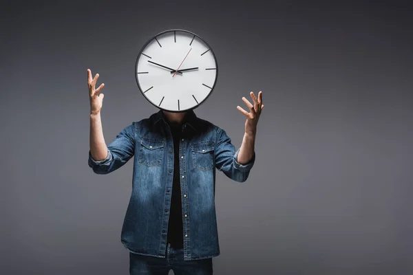 Jovem com relógio perto do rosto gesticulando em fundo cinza, conceito de gerenciamento de tempo — Fotografia de Stock
