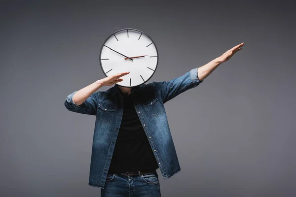 Jeune homme avec horloge près du visage gesticulant sur fond gris, concept de gestion du temps — Stock Photo