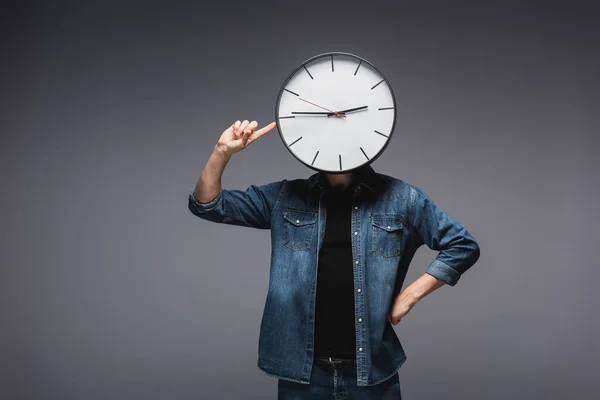 Uomo con orologio sulla testa puntato con dito su sfondo grigio, concetto di gestione del tempo — Foto stock