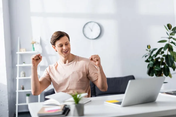 Freelance positif montrant geste oui près de l'ordinateur portable et la papeterie sur la table à la maison, gagner concept en ligne — Photo de stock