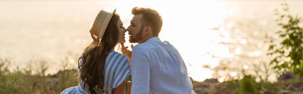 Concepto panorámico de hombre guapo y mujer atractiva en sombrero de paja cerca del lago - foto de stock