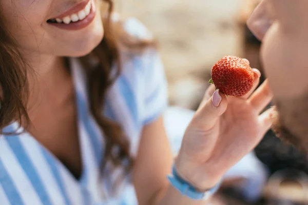 Recortado vista de feliz mujer alimentación novio con fresa - foto de stock