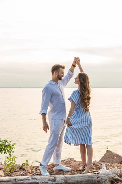 Happy couple holding hands and dancing near lake — Stock Photo
