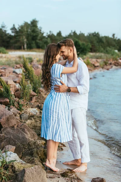 Hombre guapo y mujer feliz abrazándose cerca del lago - foto de stock