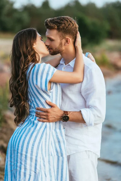 Hombre guapo y hermosa mujer con los ojos cerrados besándose fuera - foto de stock