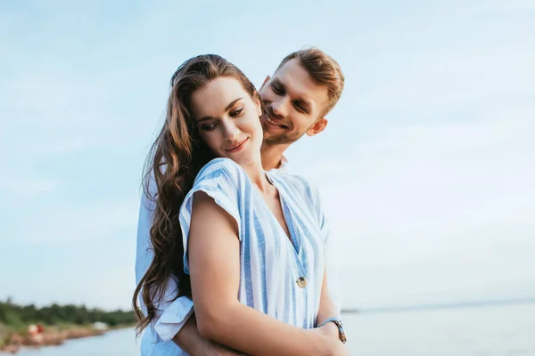Bearded man smiling and hugging attractive girl outside — Stock Photo