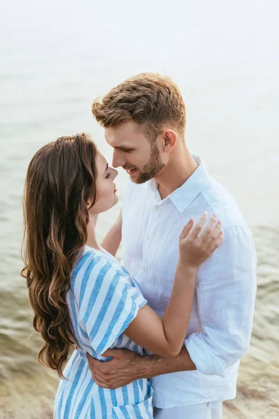 Handsome man hugging beautiful girlfriend near river — Stock Photo