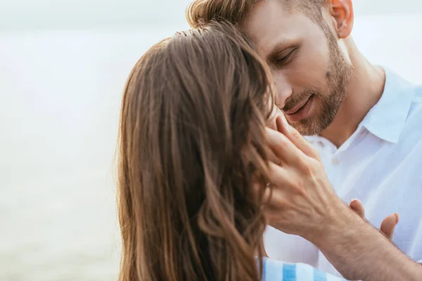 Enfoque selectivo de hombre guapo y barbudo tocando novia fuera - foto de stock