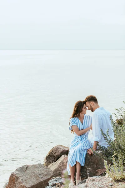 Happy couple smiling while sitting near river — Stock Photo