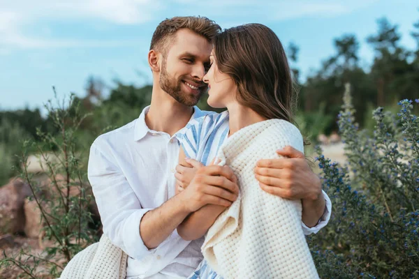 Happy and bearded man hugging cheerful girl wrapped in blanket — Stock Photo