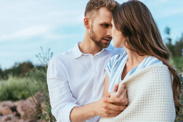 Bearded man touching girlfriend wrapped in blanket — Stock Photo