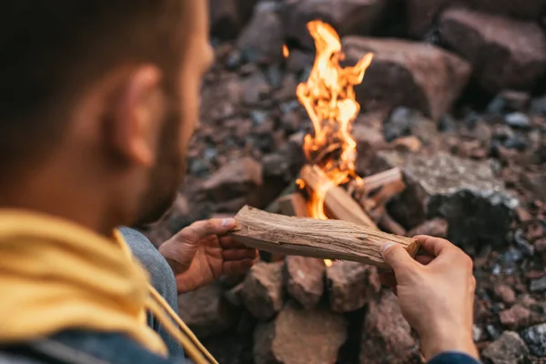Foco seletivo do homem colocando log na fogueira ardente — Fotografia de Stock