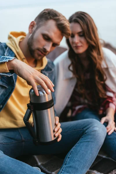 Foco seletivo de homem barbudo segurando thermos menina bonita — Fotografia de Stock