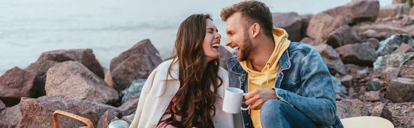 Plan panoramique de la femme riant près du petit ami avec une tasse de thé — Photo de stock