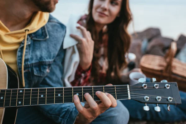 Recortado vista de barbudo hombre jugando guitarra acústica cerca de novia - foto de stock