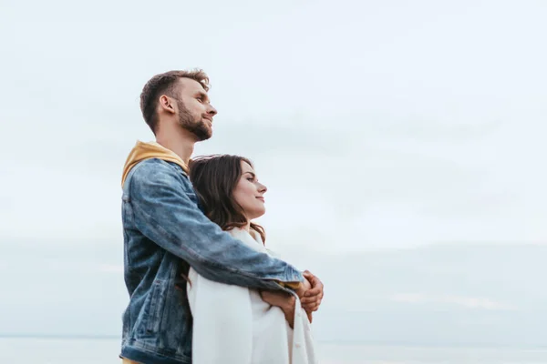 Vista laterale di felice uomo abbracciare allegra fidanzata — Foto stock