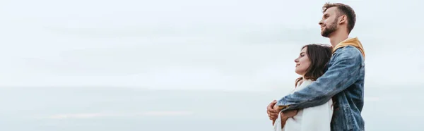 Tiro panorámico de hombre feliz abrazando novia alegre - foto de stock