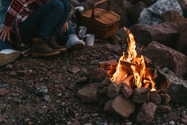 Selective focus of burning bonfire near couple sitting on rocks — Stock Photo