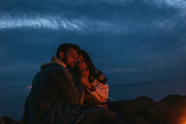 Handsome and bearded man touching attractive woman at night — Stock Photo