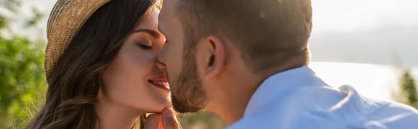 Панорамная концепция бородатого мужчины целующего счастливую молодую женщину — стоковое фото